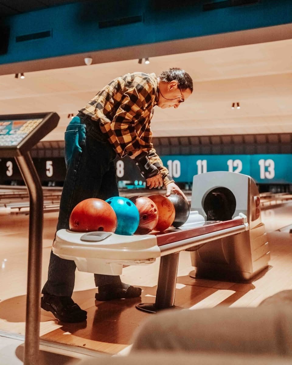 A participant choosing a bowling ball at a ten-pin bowling alley.