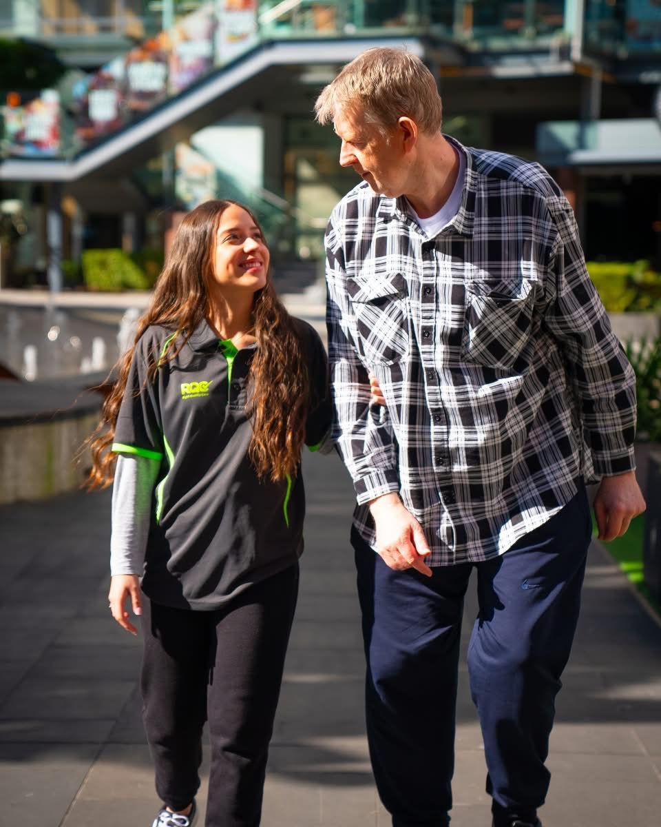 A Right Quality Care support worker walking and chatting with a client outdoors.